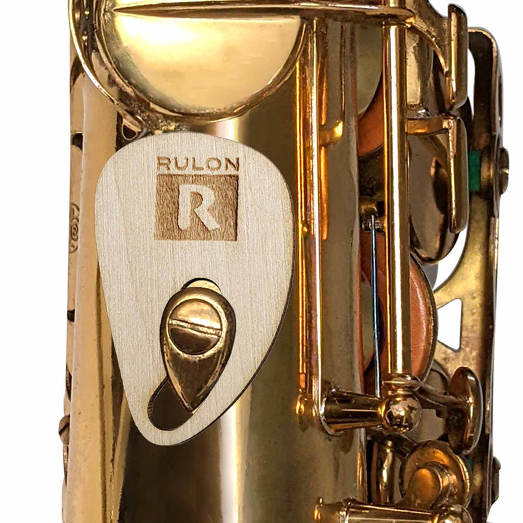 A wood trial version of the RULON saxophone thumb rest to help prevent thumb pain and wrist discomfort while playing sax.