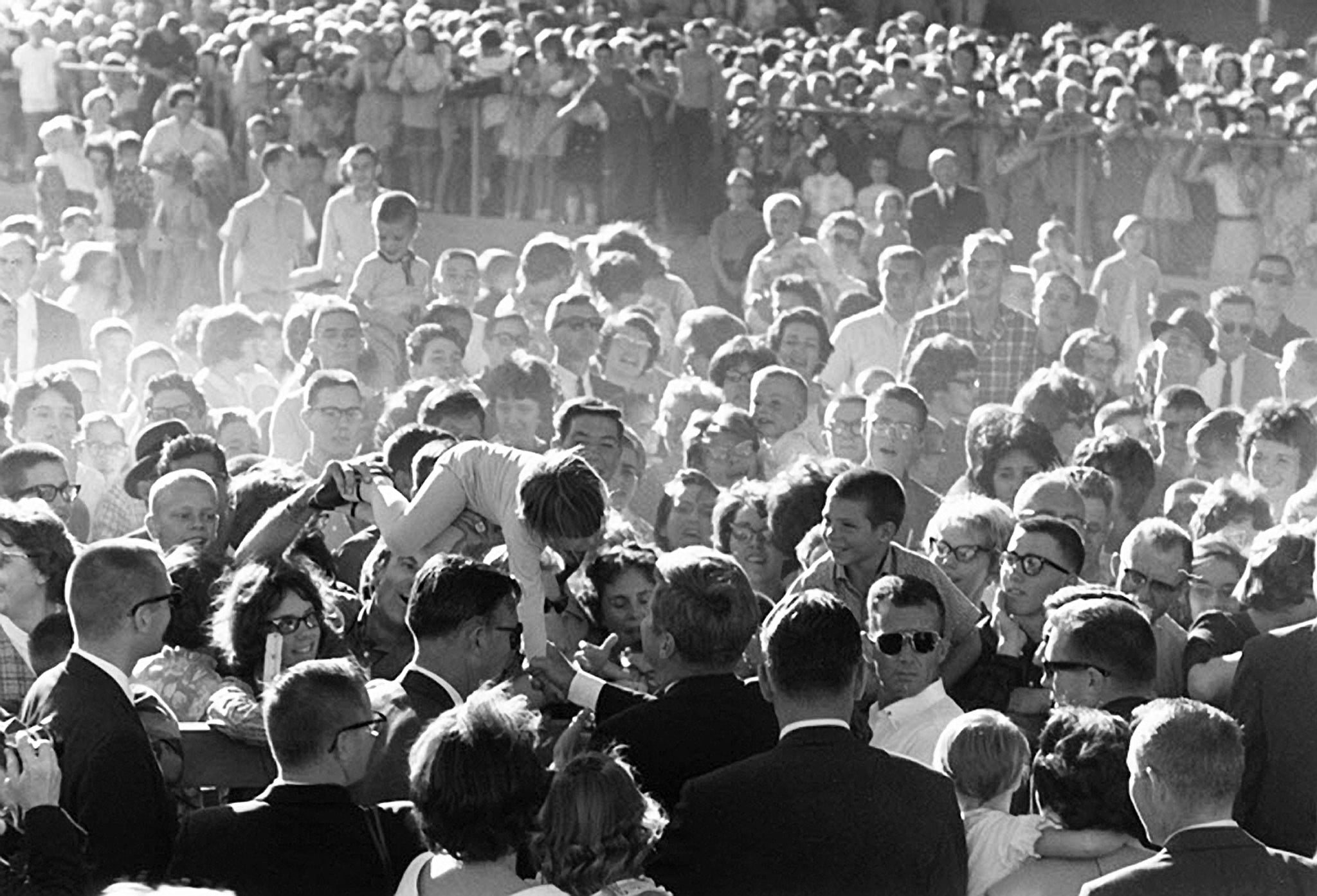 A young girl is lifted above the crowd to shake hands with President Kennedy during the President’s “Conservation Tour” of Western States, Billings, September 1963. -- COURTESY CECIL STOUGHTON