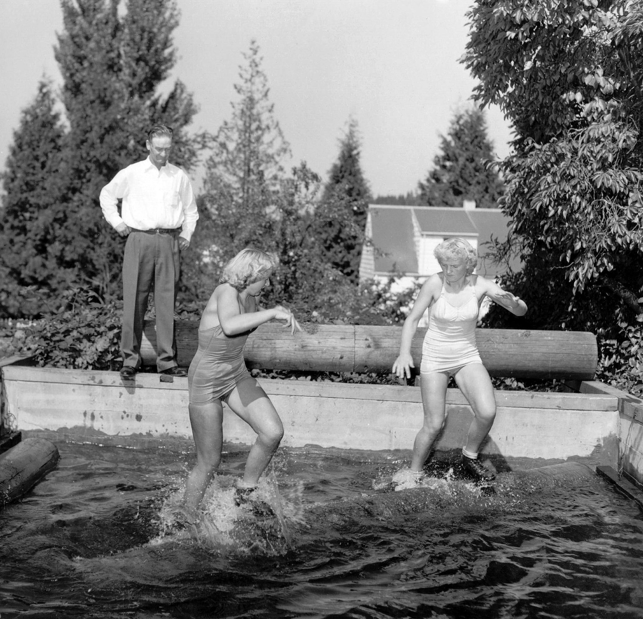 World Champion log rolling sisters Charlotte Hansen (left) and Virginia Hansen (right) practice under the direction of their father, Frank Hansen. The Hansen sisters of Toutle often faced each other as they traveled the country competing and performing at logging shows throughout the 1950s. -- Courtesy Darcy Mitchem