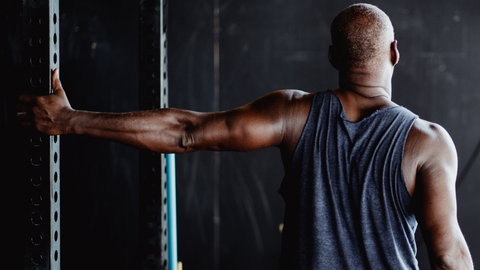 Man with his back to the camera, arm extended to the side in a chest stretch