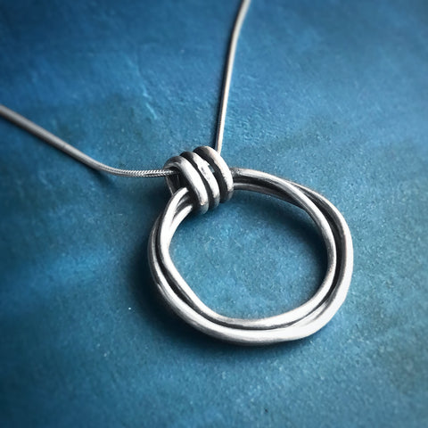 Silver Zen Coil Necklace on a blue background.