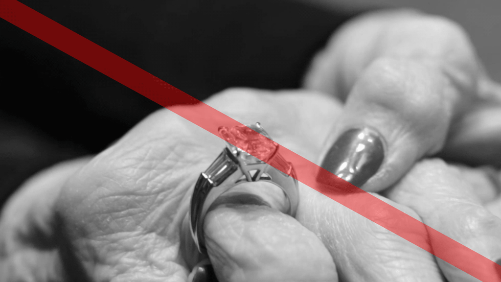 Close-up of a woman struggling to fit a tight ring on her swollen knuckle, emphasizing the need for GlidesOn™ technology by Lester Lampert for adaptable ring sizes.