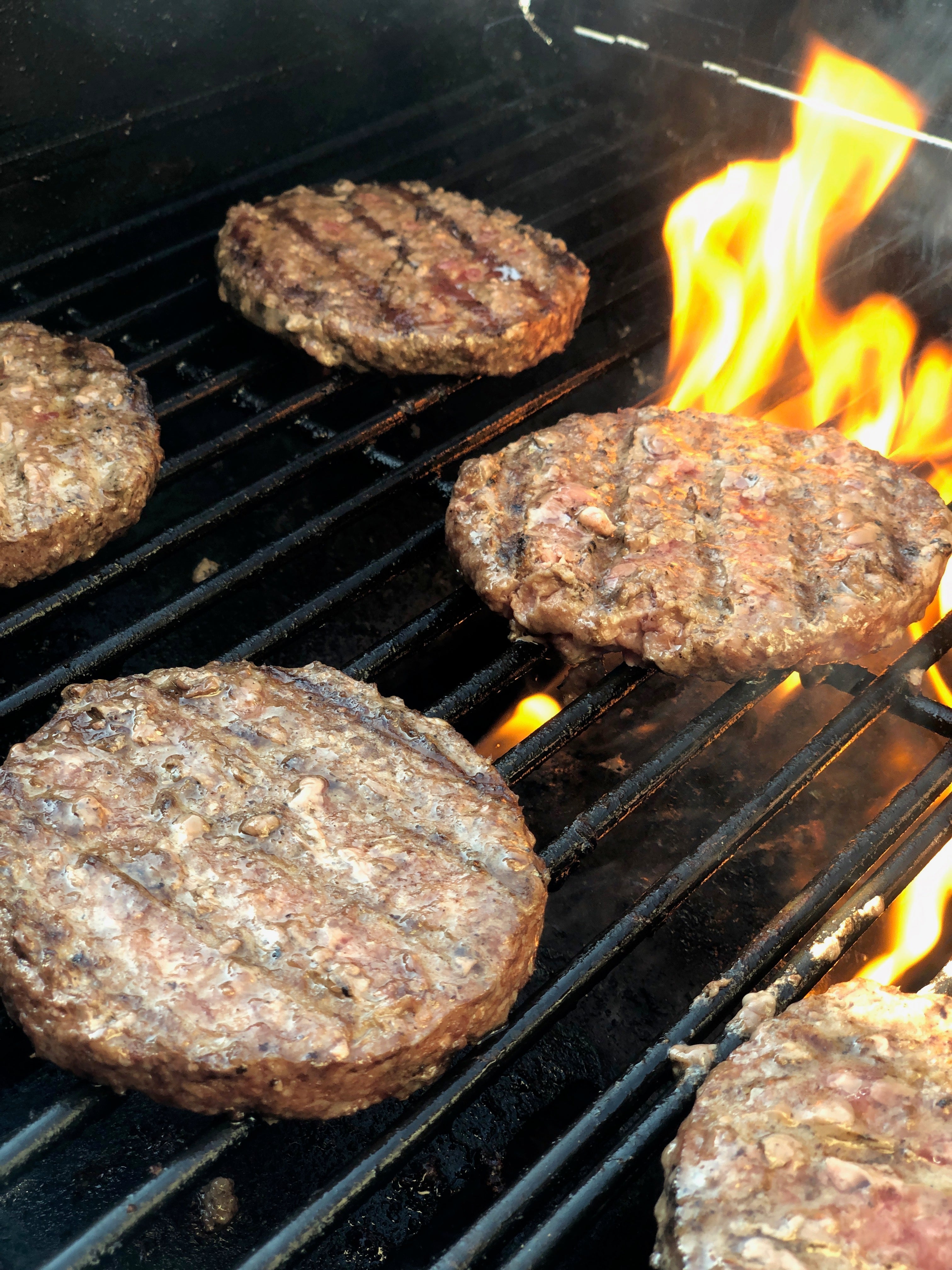 Burger Patties on a Grill with Fire Showing