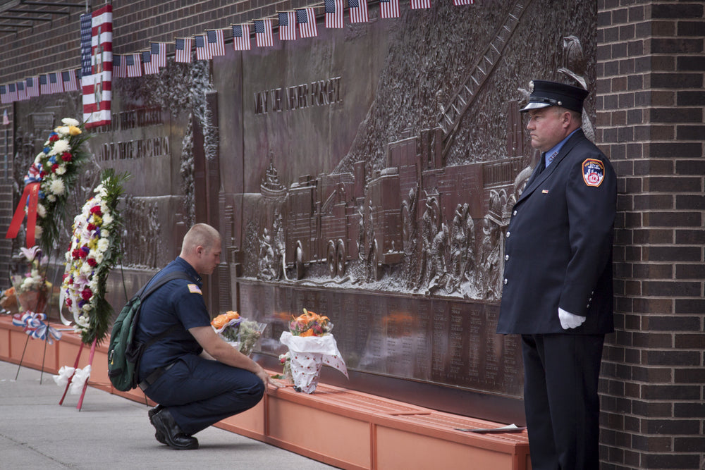 A firefighter kneels to pay respect at the Memorial Wall at FDNY Engine 10 Ladder 10 House. The firehouse is direct across from the World Trade Center site.
