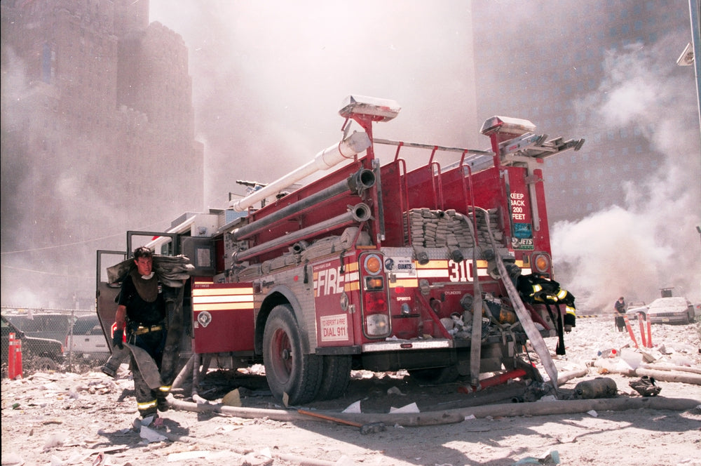 A New York City firefighter carrying a fire hose. They are near the area known as Ground Zero following the collapse of the Twin Towers.