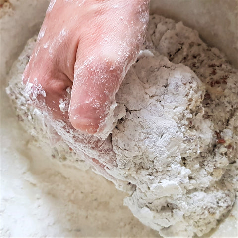 hand kneading bread in a bowl