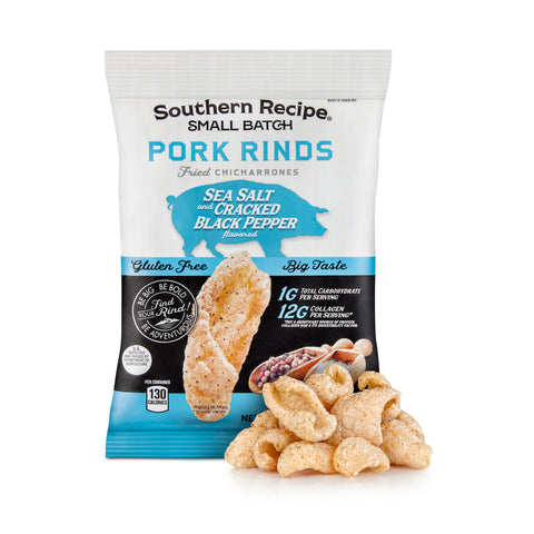 Blue and white package of Southern Recipe Small Batch Sea Salt and Cracked Black Pepper Pork Rinds on a white background with a pile of sea salt and cracked black pepper pork rinds surrounding it. 