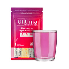 Ultima Replenisher Keto Electrolyte drink mix in pink package beside a glass of ultima replenisher keto drink mix in a clear glass. 