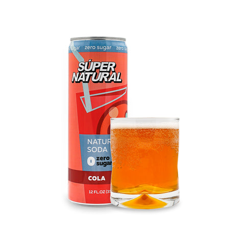 A red can of Super Natural Zero Sugar Cola on a white background beside a clear glass of Super Natural sugar free cola 