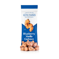 White and blue package of Keto Farms Blueberry Vanilla Keto Candied nuts with a pile of blueberry vanilla flavored cashews beside it. 