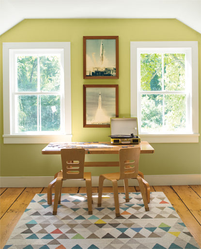 A kids' room with two windows features a portable turntable-topped desk set against a light green color wall.