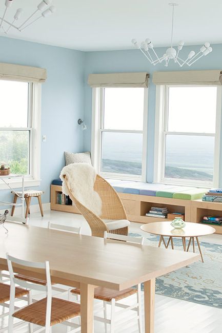 A light blue-painted room with sweeping views and a blonde wood dining table.