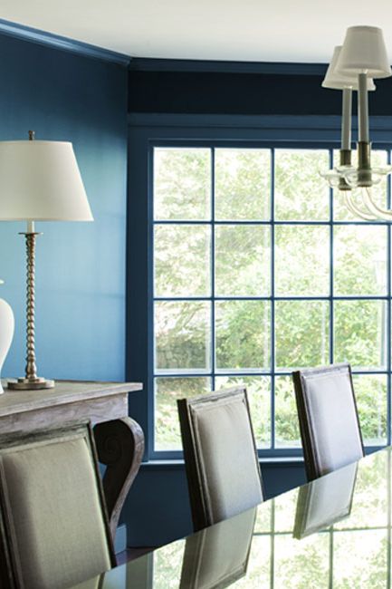 An all-blue painted dining room with chandelier.