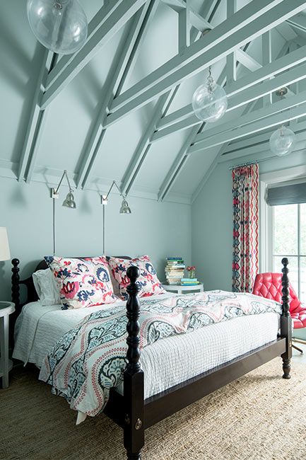 A blue-painted bedroom with four poster bed underneath vaulted ceilings.