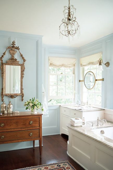 A light blue-painted bathroom with vintage mirror and sideboard.