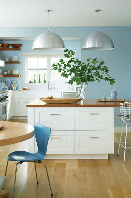 A contemporary kitchen with light blue-painted walls and white cabinets.