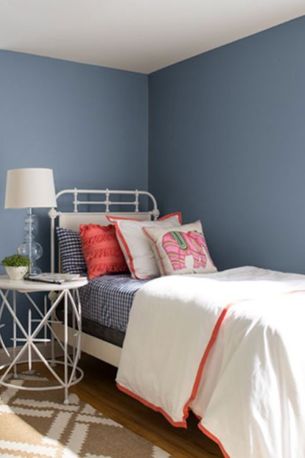 A bedroom with blue-painted walls and white trim with orange accents.