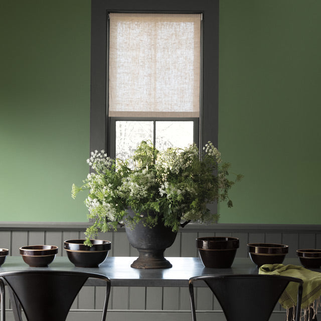 Green painted walls lighten this dining room with dark grey trim, wainscoting and table.