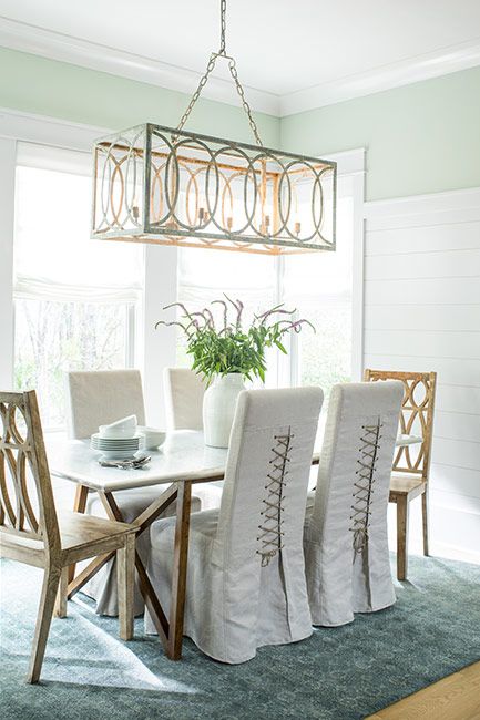 A delicate green-painted dining room with pendant light and teal rug.