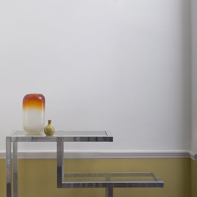 Off-white walls with yellow trim, modern end table and mobile on the ceiling.