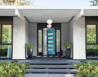 A modern light gray home with black window trim and a vibrant blue front door.