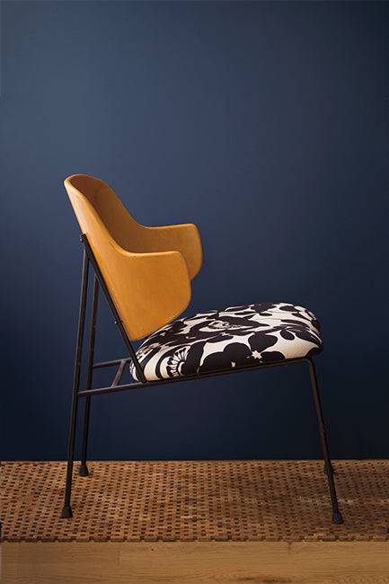 Navy blue walls with a metal chair featuring a leather back and a black and white seat cushion.