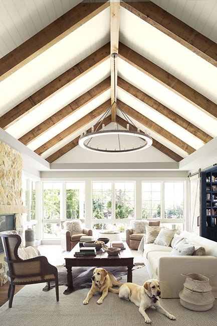 A naturally lit living room with neutral accents and high wood beamed ceiling