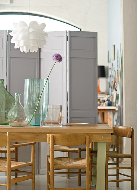 A dining area with wood table, four chairs, and a greige partition.