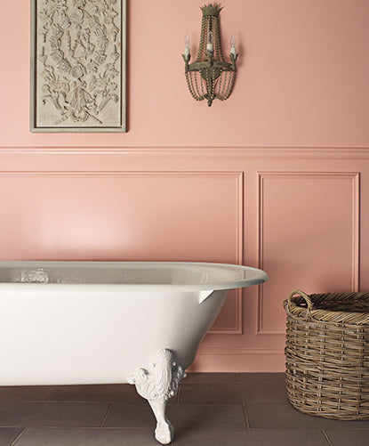 Bold pink-painted bathroom walls with matching wainscoting and a white clawfoot tub.
