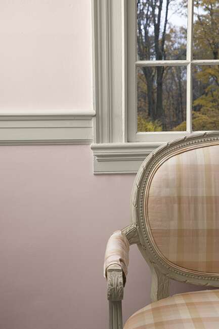 Muted pink-painted walls with off-white window trim and a plaid chair.