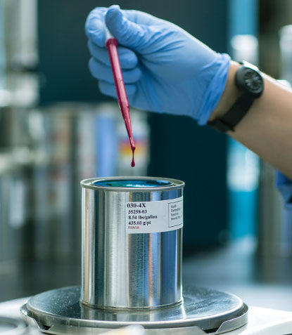 A chemist takes a sample of paint for testing.