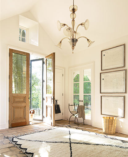 A white painted entryway in Capri Coast OC-87 features vaulted ceilings and a chandelier.