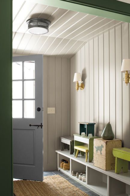 A white painted mudroom, with forest green trim and built in cubbies.