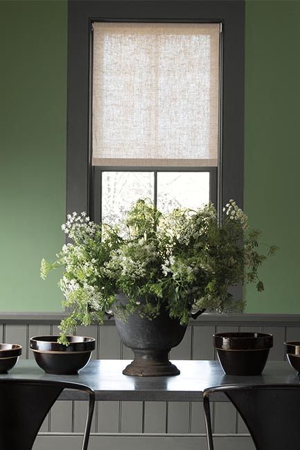 Green painted walls lightens this dining room with dark gray trim, wainscoting and table.