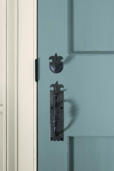 A light blue-painted paneled door with a traditional black handle.