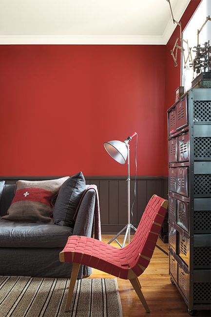 A red living room with brown wainscoting and a contemporary red woven chair.