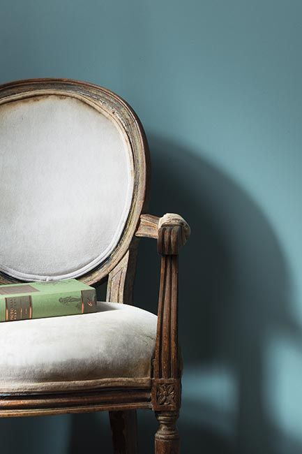 A pale blue-painted wall with a traditional round back chair.