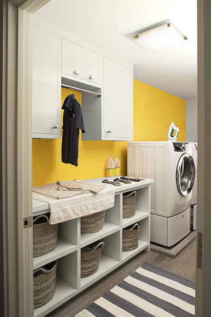 Laundry room with white cabinets and a yellow wall painted in Sunshine 2021-30.