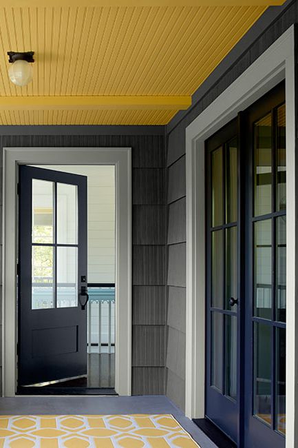 A covered porch area with a yellow ceiling painted in Marblehead Gold 2120-30.