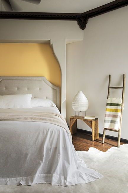 A neutral colored bedroom with a pale yellow recessed bed wall painted in York Harbor Yellow 2154-40.