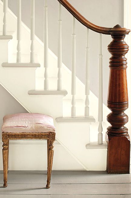 Gray walls accented by white stairs create an elegant entryway featuring three ornate stools.