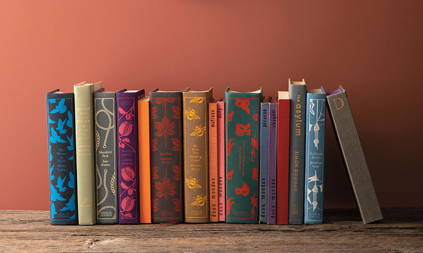 Books on a shelf under a hanging mirror, and wall painted in Rosy Peach 2089-20.