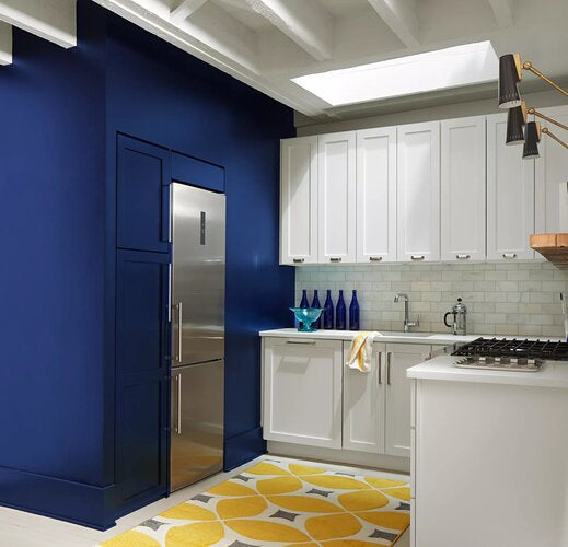 Starry Night Blue-painted accent walls in a kitchen with White Heron-painted cabinets, yellow accents, and skylight.