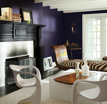 Purple living room with high-end eclectic furnishings and fireplace.