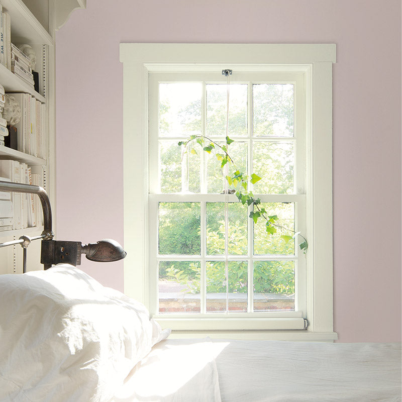 Window-filled bedroom with pink walls and metal-frame bed.