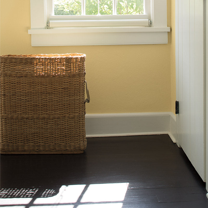 Yellow sunroom with dark hardwood floor wicker basket.