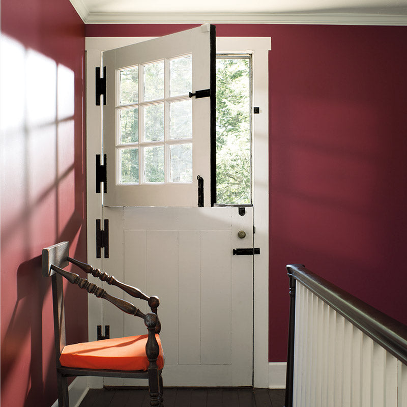Upstairs landing with banister, rich red wall and farm door.