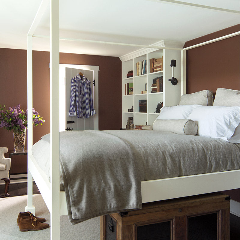Bedroom with brown walls and elevated four poster bed.