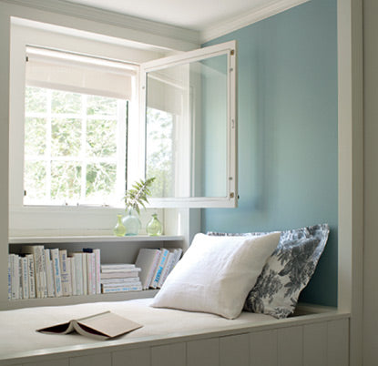 Built-in daybed with light blue wall and open window.