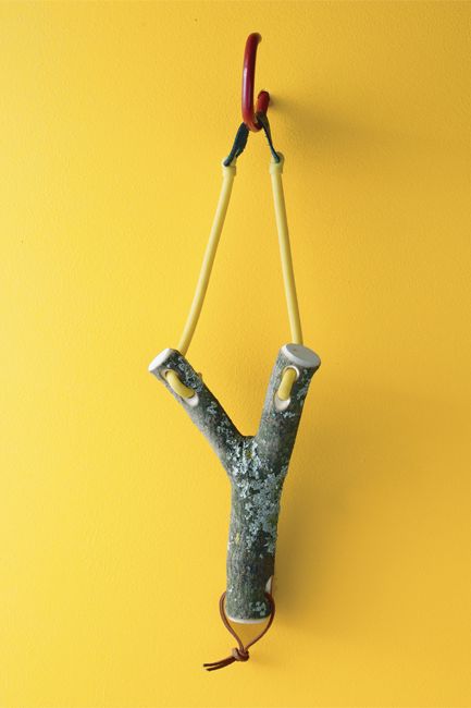 A yellow-hued wall showcases a handmade wood slingshot.